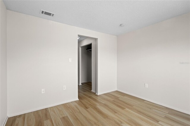 3212 Ramblewood Dr N Unit 3212, Sarasota, FL 34237 - empty room featuring light wood finished floors, baseboards, a smoke detector, and a textured ceiling