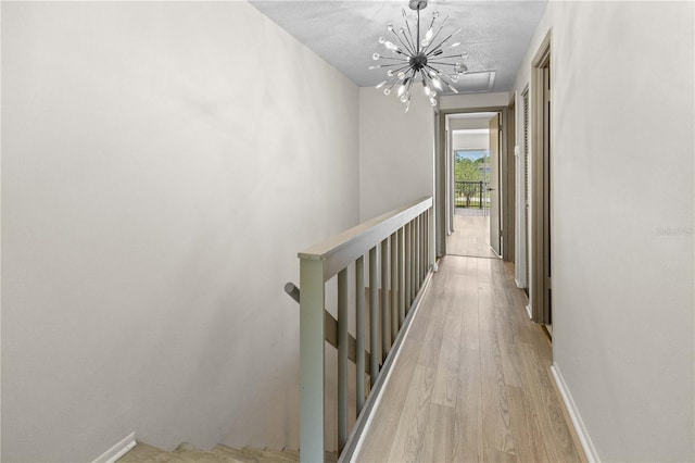 3212 Ramblewood Dr N Unit 3212, Sarasota, FL 34237 - hall featuring an upstairs landing, a chandelier, light wood-type flooring, and baseboards