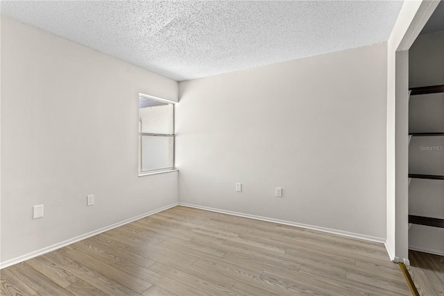 3212 Ramblewood Dr N Unit 3212, Sarasota, FL 34237 - unfurnished room with a textured ceiling, light wood-style floors, and baseboards
