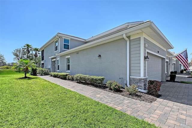 1017 Tidewater Shores Loop Unit 1017, Bradenton, FL 34208 - view of side of property with a yard, stucco siding, a garage, and decorative driveway