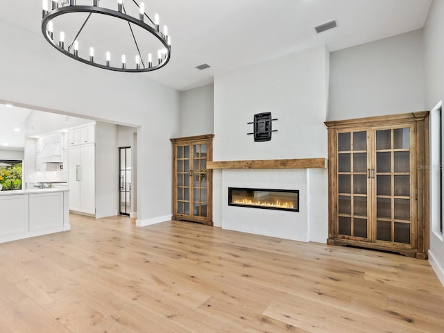 180 Lookout Point Dr, Osprey, FL 34229 - unfurnished living room featuring light wood-style floors, a glass covered fireplace, and a chandelier