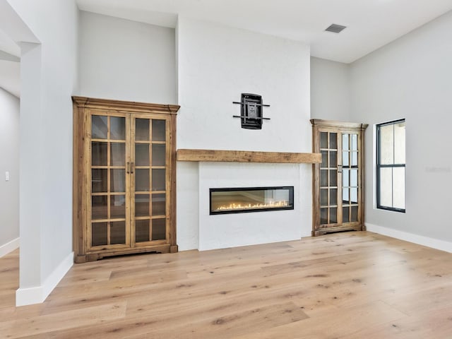 180 Lookout Point Dr, Osprey, FL 34229 - unfurnished living room featuring wood finished floors and a glass covered fireplace