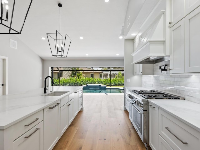 180 Lookout Point Dr, Osprey, FL 34229 - kitchen featuring double oven range, custom exhaust hood, backsplash, white cabinetry, and light wood-style flooring