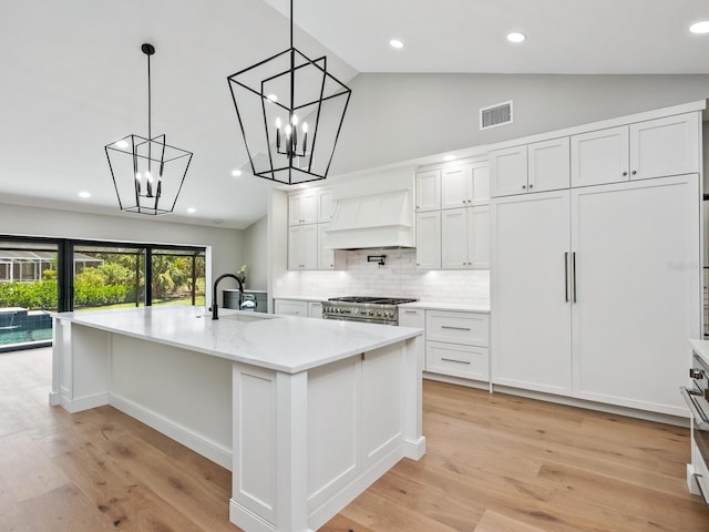 180 Lookout Point Dr, Osprey, FL 34229 - kitchen featuring custom range hood, white cabinets, backsplash, light wood-type flooring, and high vaulted ceiling