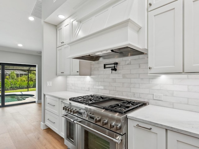 180 Lookout Point Dr, Osprey, FL 34229 - kitchen with range with two ovens, custom exhaust hood, backsplash, recessed lighting, and light stone countertops