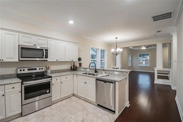 1420 E Frierson Ave, Tampa, FL 33603 - kitchen featuring stainless steel appliances, a sink, a peninsula, a chandelier, and white cabinetry