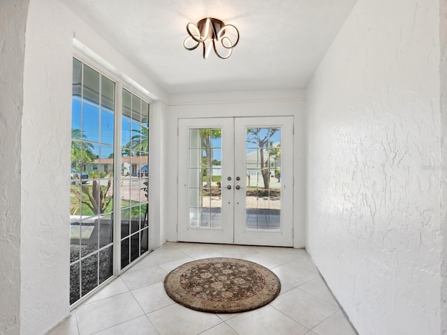 7779 Holiday Dr N, Sarasota, FL 34231 - entryway with french doors, a textured wall, healthy amount of natural light, a chandelier, and tile patterned floors