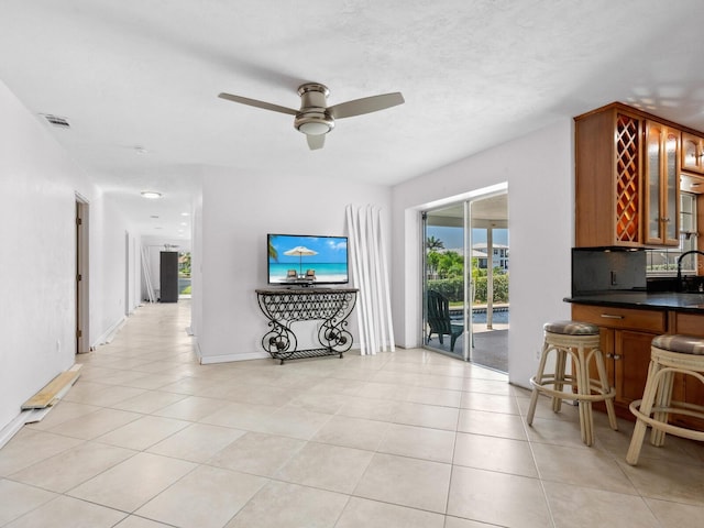 7779 Holiday Dr N, Sarasota, FL 34231 - living room featuring bar with sink, ceiling fan, light tile patterned floors, and baseboards