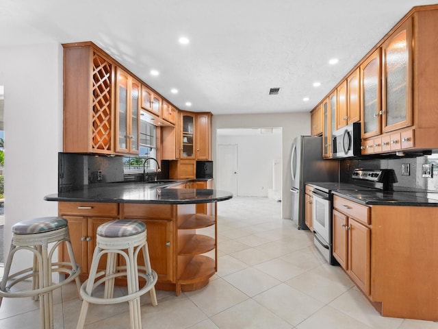 7779 Holiday Dr N, Sarasota, FL 34231 - kitchen featuring appliances with stainless steel finishes, recessed lighting, a sink, a peninsula, and decorative backsplash