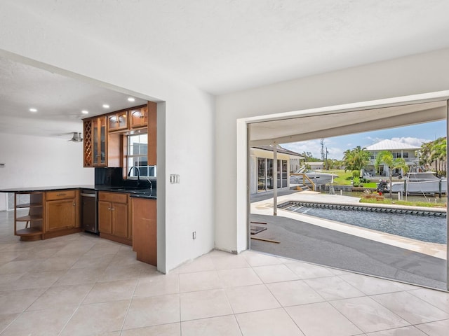 7779 Holiday Dr N, Sarasota, FL 34231 - kitchen with dark countertops, a sink, recessed lighting, brown cabinets, and a peninsula