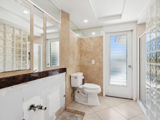 7779 Holiday Dr N, Sarasota, FL 34231 - bathroom with toilet, tile patterned flooring, tile walls, healthy amount of natural light, and an enclosed shower
