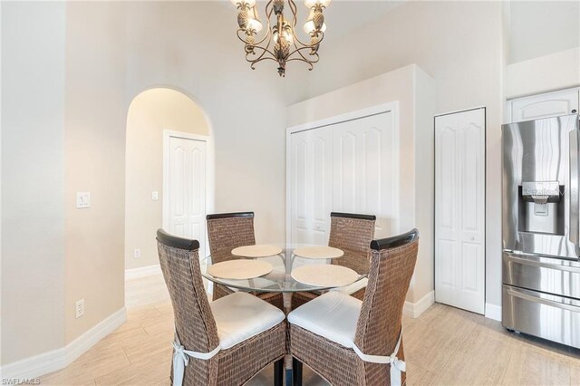 10202 L Pavia Blvd Unit 10202, Venice, FL 34292 - dining space with a high ceiling, a chandelier, baseboards, light wood-style floors, and arched walkways