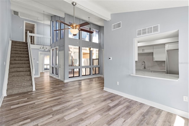 800 S Blvd Of The Presidents Unit 5, Sarasota, FL 34236 - unfurnished living room with ceiling fan, high vaulted ceiling, wood finished floors, stairs, and baseboards