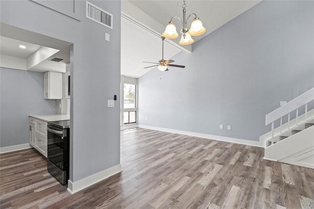 800 S Blvd Of The Presidents Unit 5, Sarasota, FL 34236 - kitchen with stainless steel range with electric stovetop, wood finished floors, white cabinetry, baseboards, and high vaulted ceiling