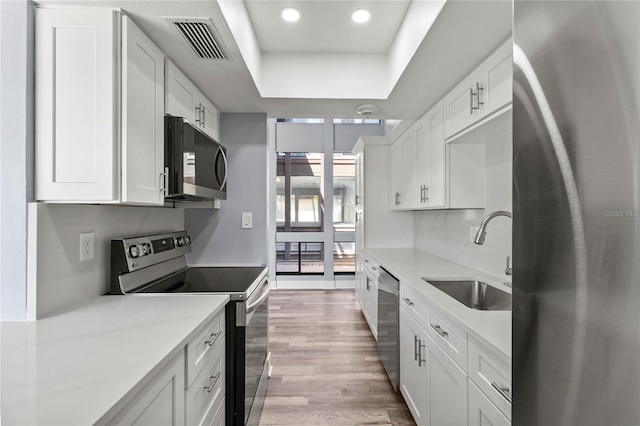 800 S Blvd Of The Presidents Unit 5, Sarasota, FL 34236 - kitchen featuring appliances with stainless steel finishes, a sink, a tray ceiling, white cabinetry, and light countertops