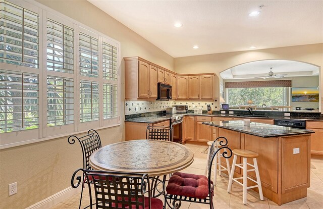 6552 Moorings Point Cir Unit 201, Lakewood Ranch, FL 34202 - kitchen featuring black appliances, a sink, a ceiling fan, tasteful backsplash, and a kitchen island