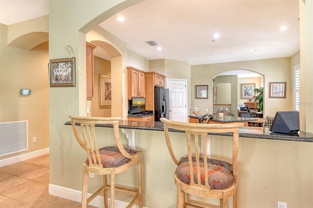 6552 Moorings Point Cir Unit 201, Lakewood Ranch, FL 34202 - kitchen with refrigerator with ice dispenser, a kitchen bar, recessed lighting, light tile patterned floors, and dark stone counters