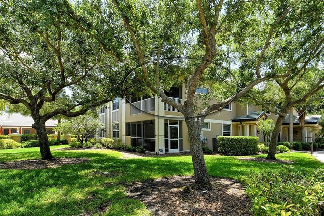 6552 Moorings Point Cir Unit 201, Lakewood Ranch, FL 34202 - rear view of property featuring a balcony, a yard, stucco siding, and a sunroom
