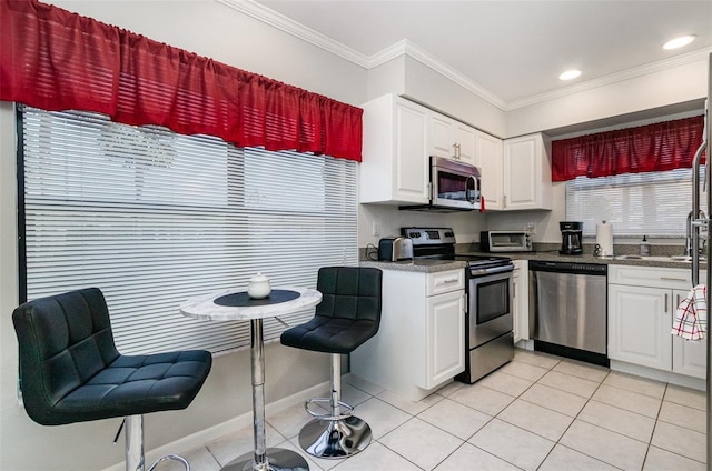 716 SE 12th Ct Unit 31, Cape Coral, FL 33990 - kitchen featuring appliances with stainless steel finishes, light tile patterned floors, white cabinets, and crown molding