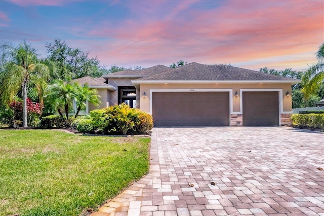 15208 21st Ave E, Bradenton, FL 34212 - view of front facade featuring stucco siding, decorative driveway, a garage, and a front lawn