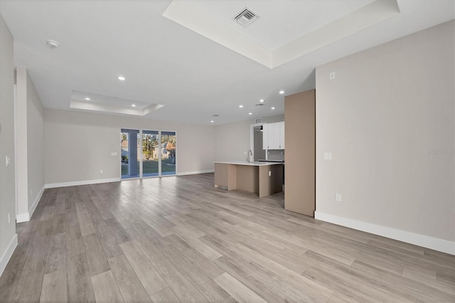 2258 Margaret Ln, North Port, FL 34286 - unfurnished living room with a tray ceiling, light wood-type flooring, and recessed lighting