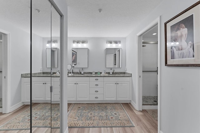 7160 Cedar Hollow Cir, Bradenton, FL 34203 - full bath with wood finished floors, a stall shower, baseboards, double vanity, and a textured ceiling