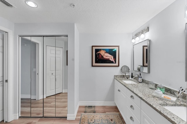 7160 Cedar Hollow Cir, Bradenton, FL 34203 - bathroom with a textured ceiling, wood finished floors, baseboards, and double vanity