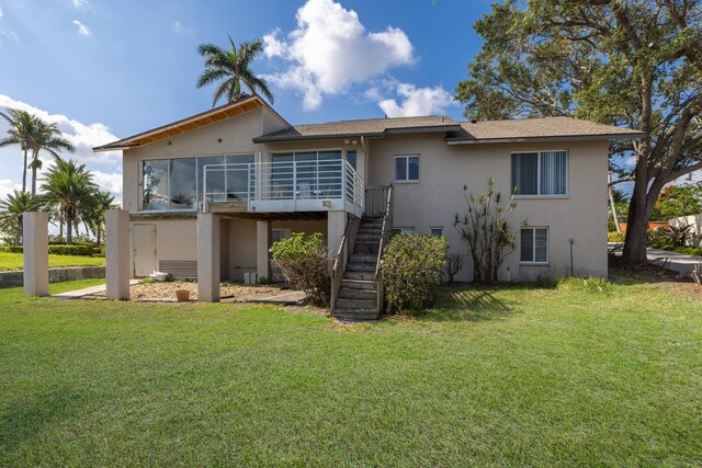 5912 Riverview Ln, Bradenton, FL 34209 - rear view of property featuring stucco siding, stairs, a sunroom, and a yard
