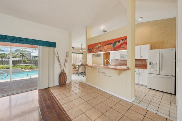 321 Sorrento Dr, Osprey, FL 34229 - kitchen featuring white appliances, white cabinets, a kitchen bar, backsplash, and a sink