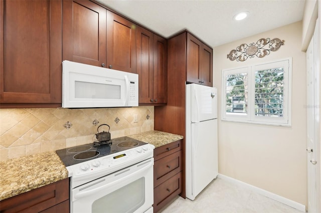 1170 Bird Bay Way Unit 206, Venice, FL 34285 - kitchen with white appliances, tasteful backsplash, baseboards, light stone countertops, and brown cabinetry