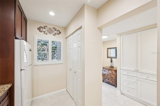 1170 Bird Bay Way Unit 206, Venice, FL 34285 - kitchen with freestanding refrigerator, light stone counters, baseboards, light tile patterned flooring, and dark brown cabinetry