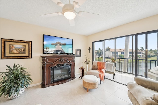 1170 Bird Bay Way Unit 206, Venice, FL 34285 - living area with ceiling fan, a textured ceiling, a glass covered fireplace, light tile patterned floors, and baseboards