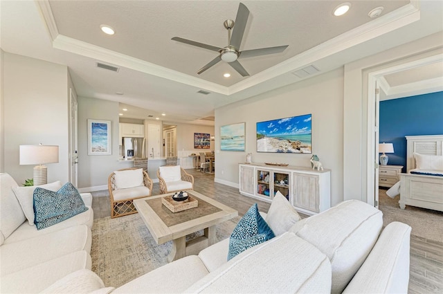 3027 Formia Ct, Lakewood Ranch, FL 34211 - living area featuring a tray ceiling, ornamental molding, light wood-type flooring, a ceiling fan, and recessed lighting