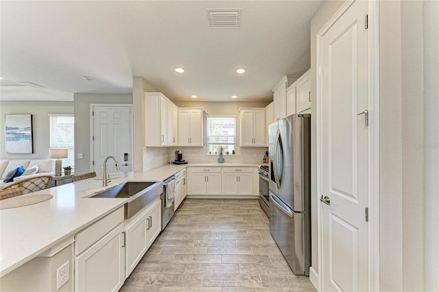 3027 Formia Ct, Lakewood Ranch, FL 34211 - kitchen featuring stainless steel appliances, open floor plan, light wood-style floors, white cabinetry, and recessed lighting