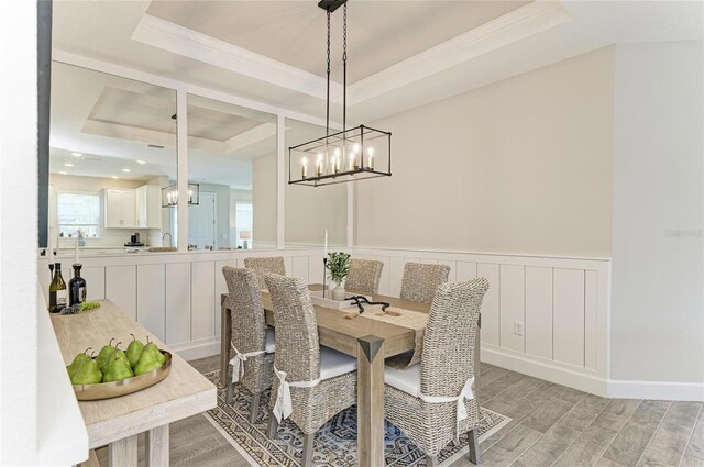 3027 Formia Ct, Lakewood Ranch, FL 34211 - dining area featuring a raised ceiling, light wood-type flooring, crown molding, wainscoting, and a chandelier