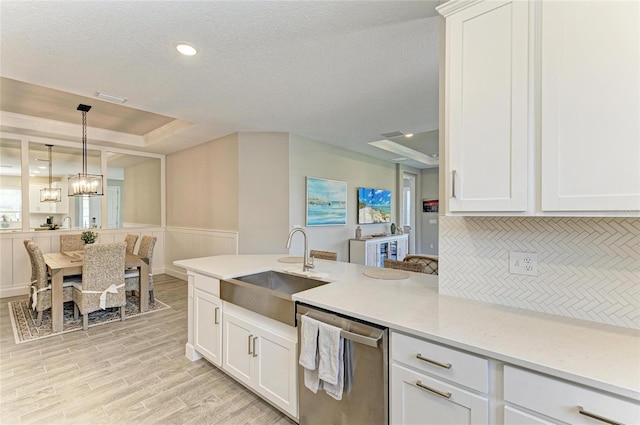 3027 Formia Ct, Lakewood Ranch, FL 34211 - kitchen featuring stainless steel dishwasher, a raised ceiling, light wood-type flooring, white cabinetry, and a chandelier