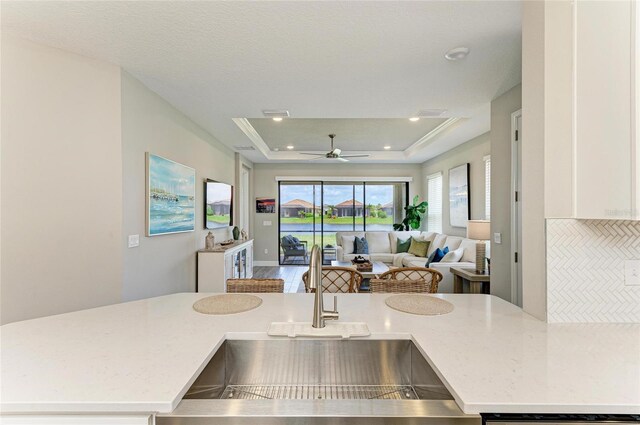 3027 Formia Ct, Lakewood Ranch, FL 34211 - kitchen featuring open floor plan, a tray ceiling, ceiling fan, recessed lighting, and light stone counters