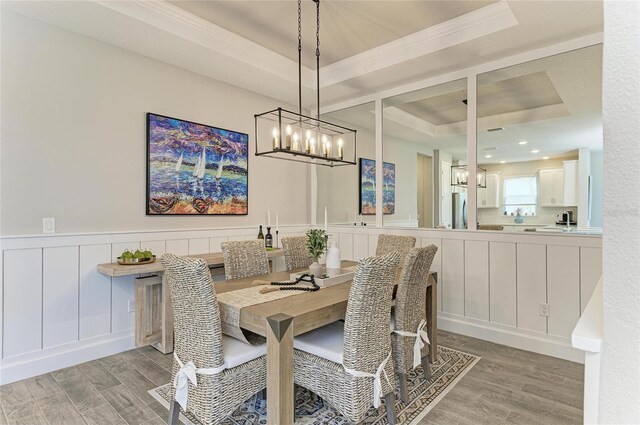 3027 Formia Ct, Lakewood Ranch, FL 34211 - dining room featuring a raised ceiling, light wood-style floors, a chandelier, crown molding, and a wainscoted wall