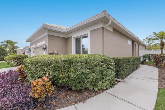 view of side of home featuring stucco siding and an attached garage