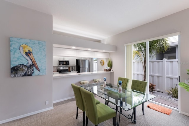 carpeted dining space featuring baseboards