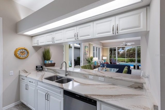 kitchen with a sink, stainless steel dishwasher, white cabinetry, baseboards, and light stone counters
