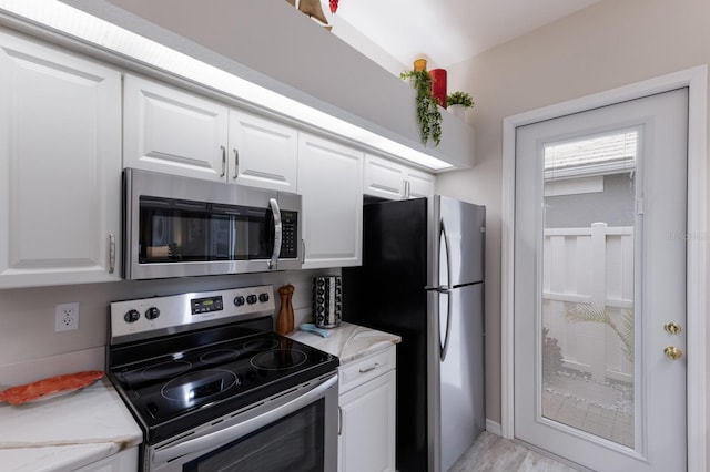 kitchen featuring stainless steel appliances, white cabinets, and light stone counters