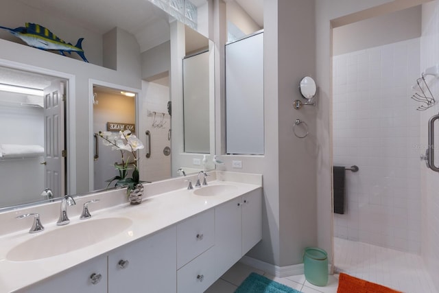 bathroom with tiled shower, tile patterned flooring, and double vanity