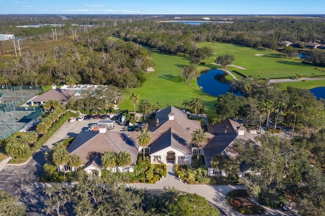 aerial overview of property's location featuring a golf course, a nearby body of water, and a tree filled landscape