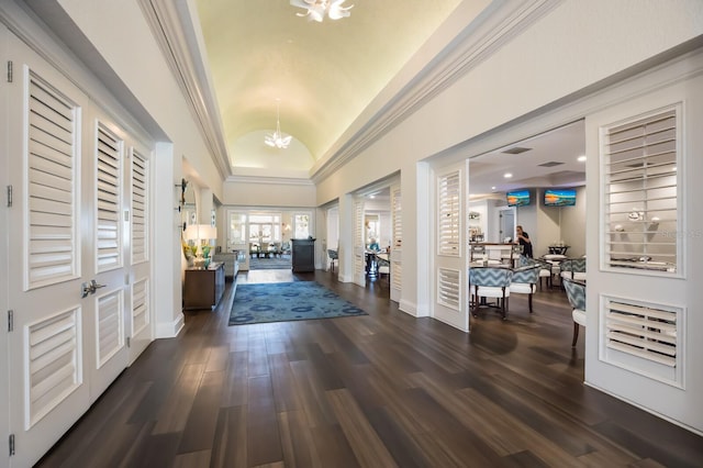 foyer featuring a chandelier, lofted ceiling, dark wood-style flooring, crown molding, and baseboards