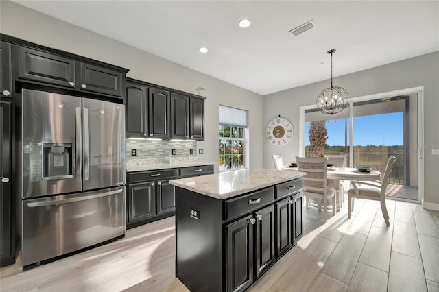 23233 Banbury Way Unit 302, Venice, FL 34293 - kitchen featuring stainless steel refrigerator with ice dispenser, dark cabinets, a chandelier, light wood-style floors, and backsplash