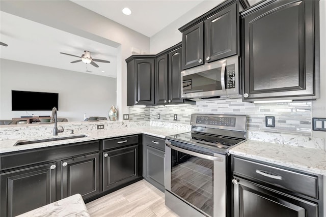 23233 Banbury Way Unit 302, Venice, FL 34293 - kitchen featuring stainless steel appliances, a sink, ceiling fan, light stone counters, and tasteful backsplash