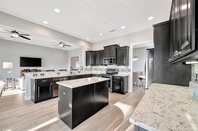 23233 Banbury Way Unit 302, Venice, FL 34293 - kitchen with appliances with stainless steel finishes, a ceiling fan, dark cabinetry, a peninsula, and backsplash