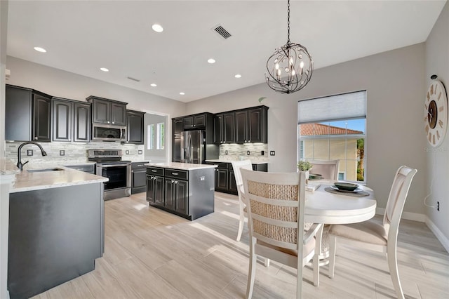 23233 Banbury Way Unit 302, Venice, FL 34293 - kitchen with appliances with stainless steel finishes, a sink, tasteful backsplash, a chandelier, and a center island