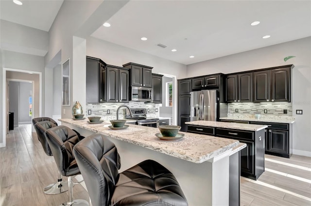 23233 Banbury Way Unit 302, Venice, FL 34293 - kitchen featuring appliances with stainless steel finishes, a peninsula, backsplash, a kitchen breakfast bar, and a center island